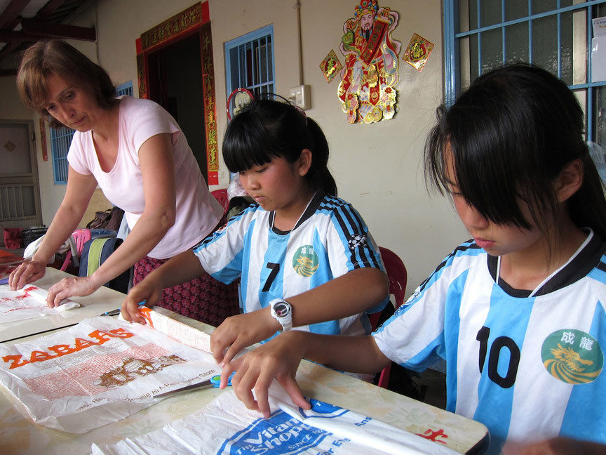 Artist Isabelle Garbani helping 6th graders at Cheng Long Elementary School cut recycled plastic bags into yarn, for crocheting the many plastic leaves she used for her installation “Invasive Species,” situated on an old house—now home to chickens and ducks—in Cheng Long village, Taiwan.