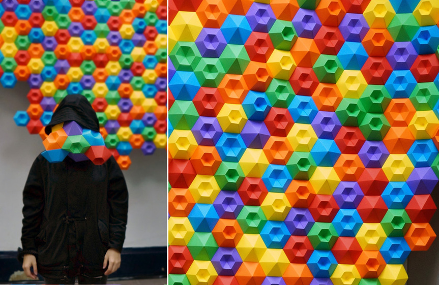 A participant in a workshop lead by Stickyline poses in front of the collaborate artwork Coast Modules / Polygon Landfilling.