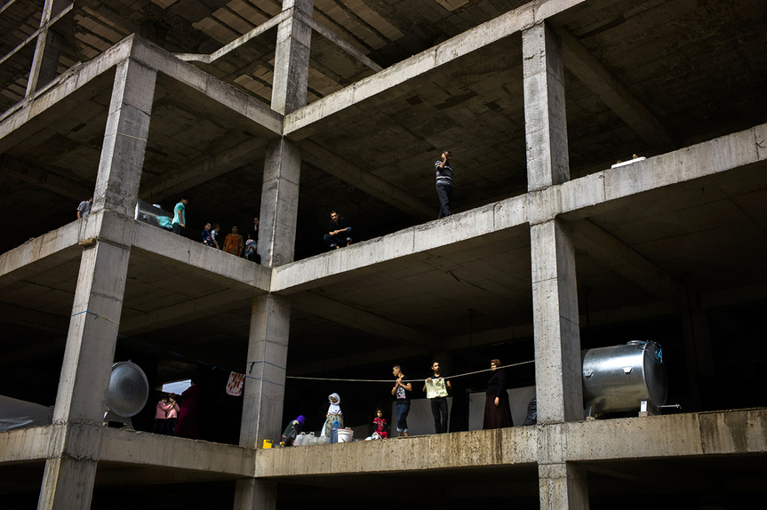 Yazidi IDP stand along the edge of an 11 story building that temporarily houses 359 people, of which 70 percent are under the age of 18 years old in Dohuk. Plastic sheets have been used to finish walls and close of the space to protect themselves from winter. There are an estimated 850,000 internally displaced people currently living in the Kurdistan Region of Iraq, having fled violence and persecution in other parts of the country. Hundreds of thousands have sought shelter in unfinished buildings, public spaces and informal settlements.Many of the half-built structures dotted throughout the region’s northern Dohuk governorate contain dozens of displaced families. They face uncomfortable and often dangerous living conditions, including a lack of adequate sanitation and insulation from the elements. With winter fast approaching, many of those living in open-sided concrete shells have only plastic sheeting, foam mattresses and blankets to protect them from the freezing rain and bitter temperatures. Courtesy the artist and the United Nations High Commissioner for Refugees, Geneva.