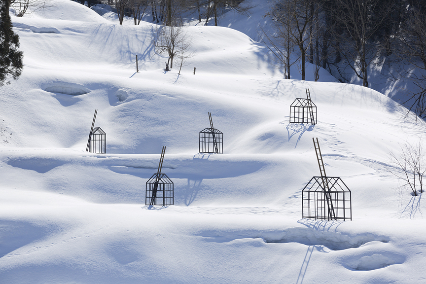 Skeletal steel houses dot the snowy landscape in Hidden Village (2017) by Finnish artist MAARIA WIRKKALA. The strategic placement of ladders indicates where the houses lie during the heaviest blizzards, when the peaks of the houses may be hidden by meters of snow. Photo by Osamu Nakamura. CourtesyArt Front Gallery, Tokyo.