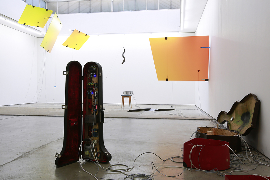 Installation view of TAMAR HARPAZ’s Crazy Delay, 2018, sound and kinetic installation; 4 mins 56 secs, violin case, rock, electroluminescent wire, drum box, wood, aluminum, string, metal case, blue silicone disc, UV prints on glass, bass guitar strings, tea cup, snare drum, stool, shofar, spoon, wood, string, steel, cello case, trombone case, flight cases, muzuza, contact microphones, electronic components, dimensions variable.