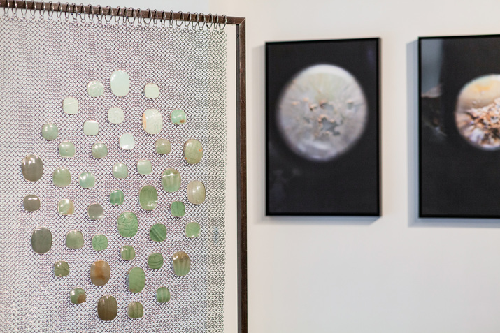 Installation view of LEELEE CHAN’s (left) Celadon Weaver, 2020, ceramic shards (Qingbai ware, Longquan ware, and Yaozhou ware) from Song to Ming dynasties (10th to 17th centuries AD), 925 silver, stainless steel chain mail, steel stand, 70 × 33 × 177 cm; and Surface Morphology, 2020, archival pigment prints mounted on aluminum frames, set of 7 prints, at “Up Close – Hollywood Road,” Hong Kong, 2020.