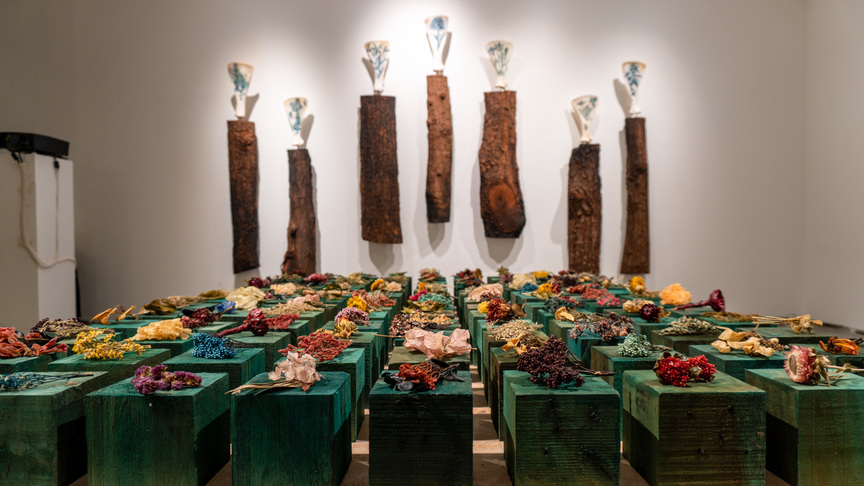 Installation view of GERALDINE JAVIER’s (front) In Memory of, 2021, encaustic dried flowers, 117 pieces of coloured wood blocks, 10 × 10 × 10 cm each; (back) Bones for Jarman (Set A), 2021, engraved cow hip bones, charred wood barks, dimensions variable, at “Five Gardens,” Artinformal Gallery, Manila, 2021.